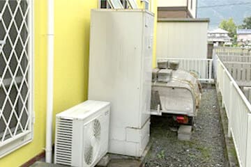 住宅の外壁沿いに設置されたエコキュートの貯湯タンクユニットと室外機の写真